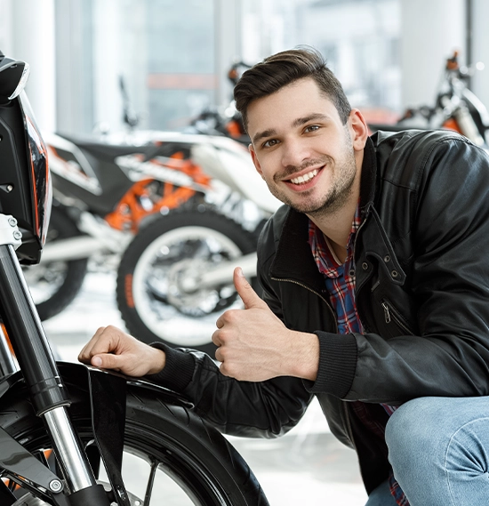 Young man smiling to showing thumbs up after checking out a motorcycle