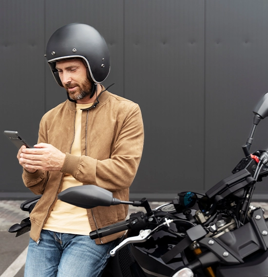 Biker wearing helmet using mobile phone standing near sport motorcycle