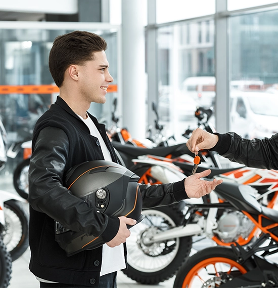 Man in a leather jacket passing motorbike keys to a motorcycle customer