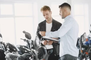 A man is applying for a loan for a new motorbike in a showroom with the salesman