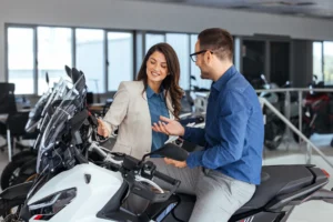 A man and a woman having a friendly discussion while checking a new motorcycle in a showroom, symbolizing excitement and interest in purchasing a new vehicle.